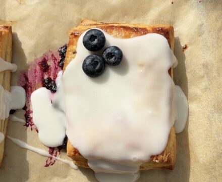 Overhead view of a lemon blueberry toaster strudel topped with a lemon glaze and fresh blueberries.