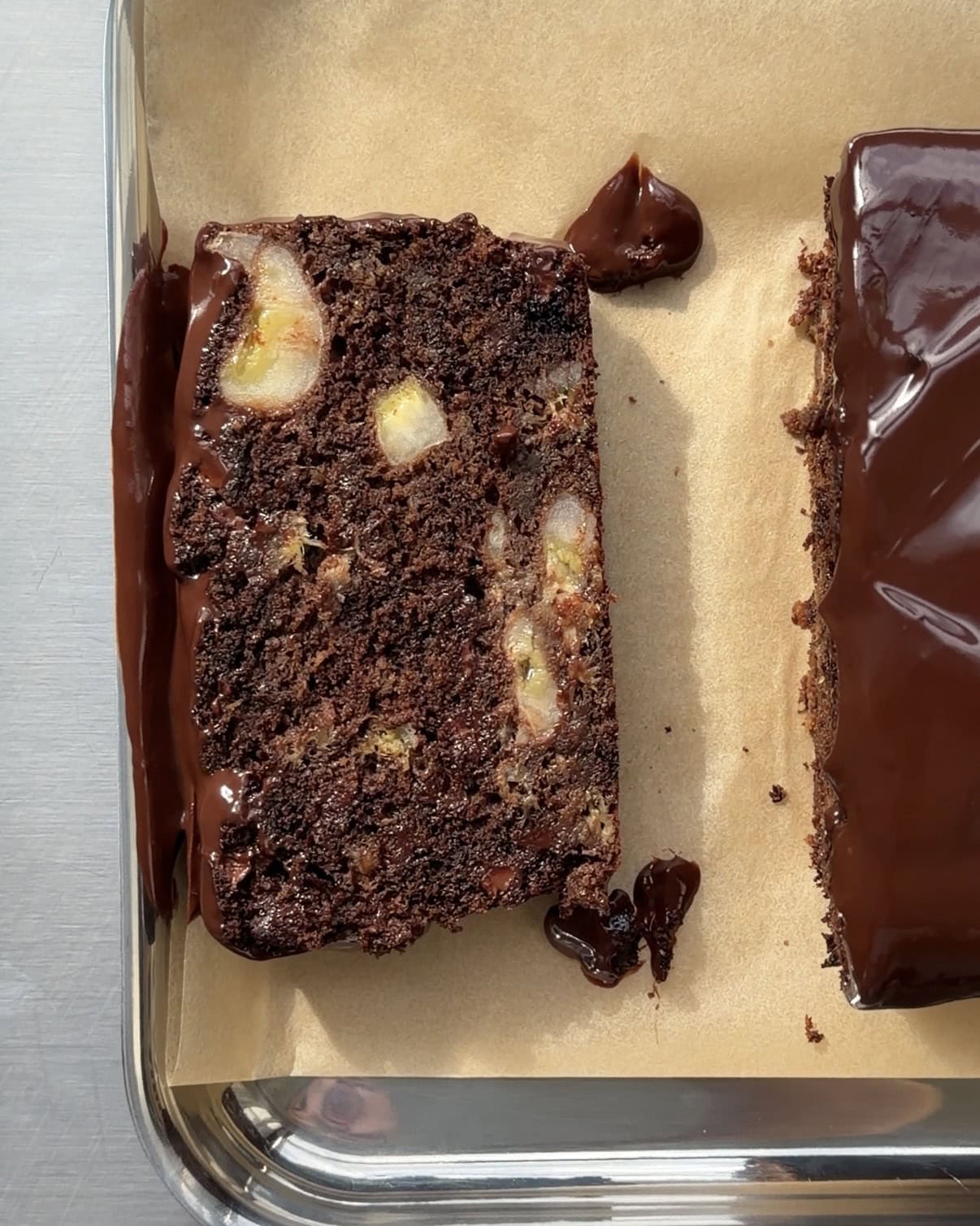 Overhead view of a slice of double chocolate banana bread with banana chunks, chocolate chips and a chocolate ganache.