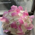Side view of a domed Berries & Cream cake decorated with whipped cream and peonie petals.