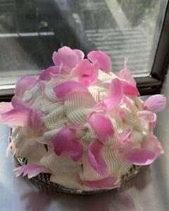 Side view of a domed Berries & Cream cake decorated with whipped cream and peonie petals.