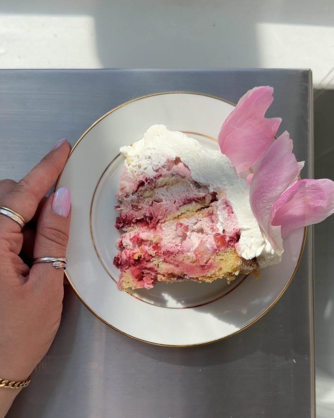 Overhead view of a slice of Berries & Cream Cake on a white and gold plate.