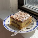 Side view of a large slice of sour cream coffee cake on a white and blue plate.
