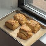 Side view of a baking sheet with four sea salt buttermilk biscuits.