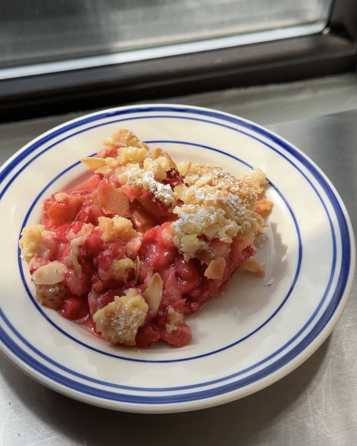 Side view of a blue and white plate topped with a rhubarb crumble.