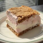 Side view of a Strawberry Ice Cream Oatmeal Cream Pie sandwich on a white and green plate.