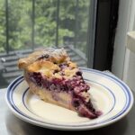 Side view of a slice of Lemon Blueberry Cheesecake Pie on a white and blue plate showing all of the layers.