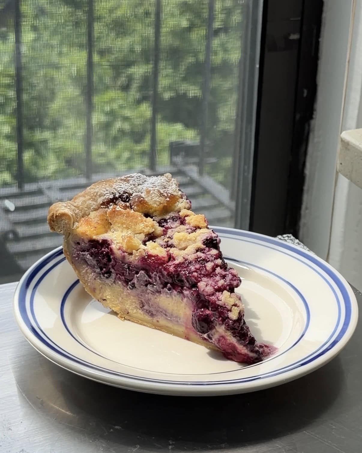 Side view of a slice of Lemon Blueberry Cheesecake Pie on a white and blue plate showing all of the layers.