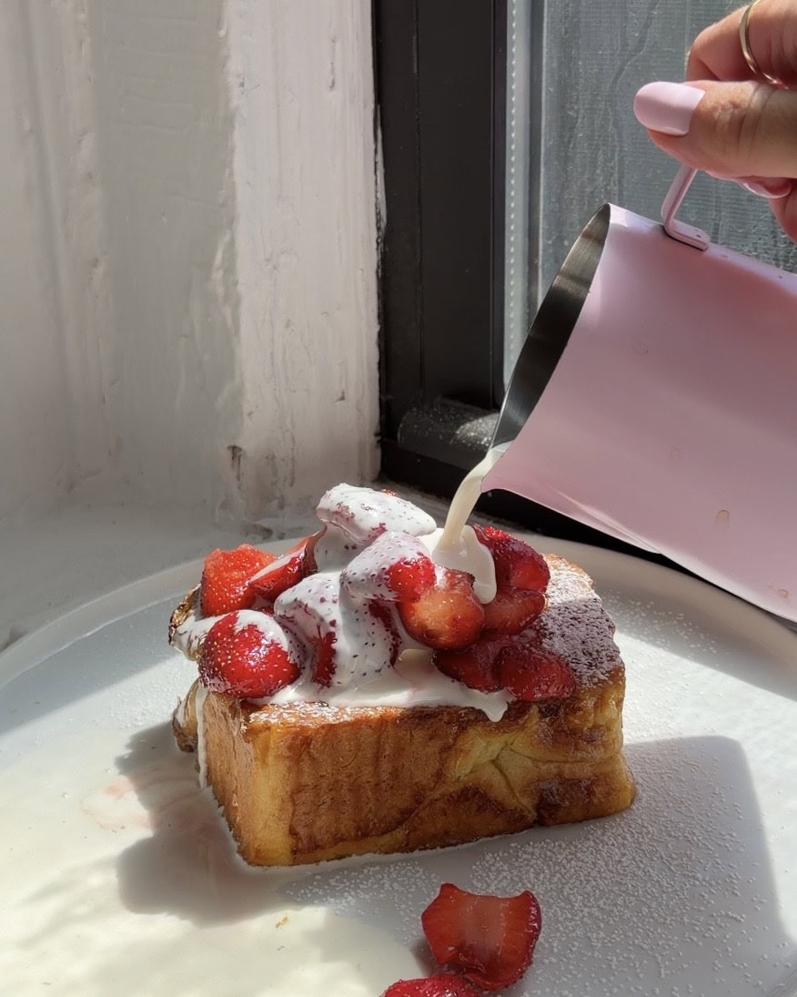 Side view of a thick slice of Brioche French toast topped with strawberries and chamomile cream.