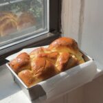 Side view of a Classic Brioche loaf in a metal pan on a window sill.