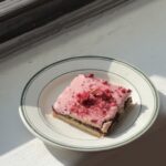 Side view of a Cherry Raspberry Jam bar with cherry glaze and freeze dried cherries on a white and green plate.