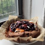 Side view of a Flourless Chocolate Cherry Cake on a piece of brown parchment.