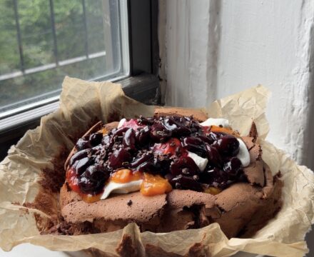 Side view of a Flourless Chocolate Cherry Cake on a piece of brown parchment.