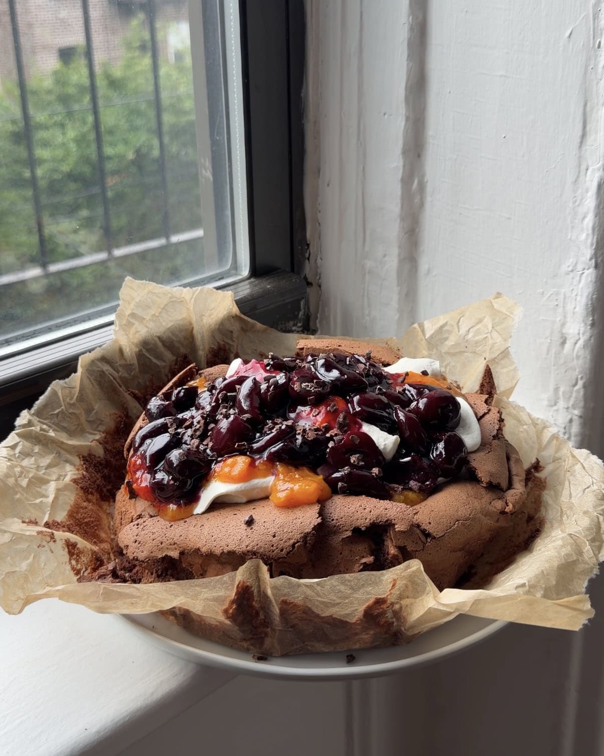 Side view of a Flourless Chocolate Cherry Cake on a piece of brown parchment.