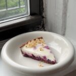 Side view of a slice of Currant Panna Cotta Tart on a white plate.