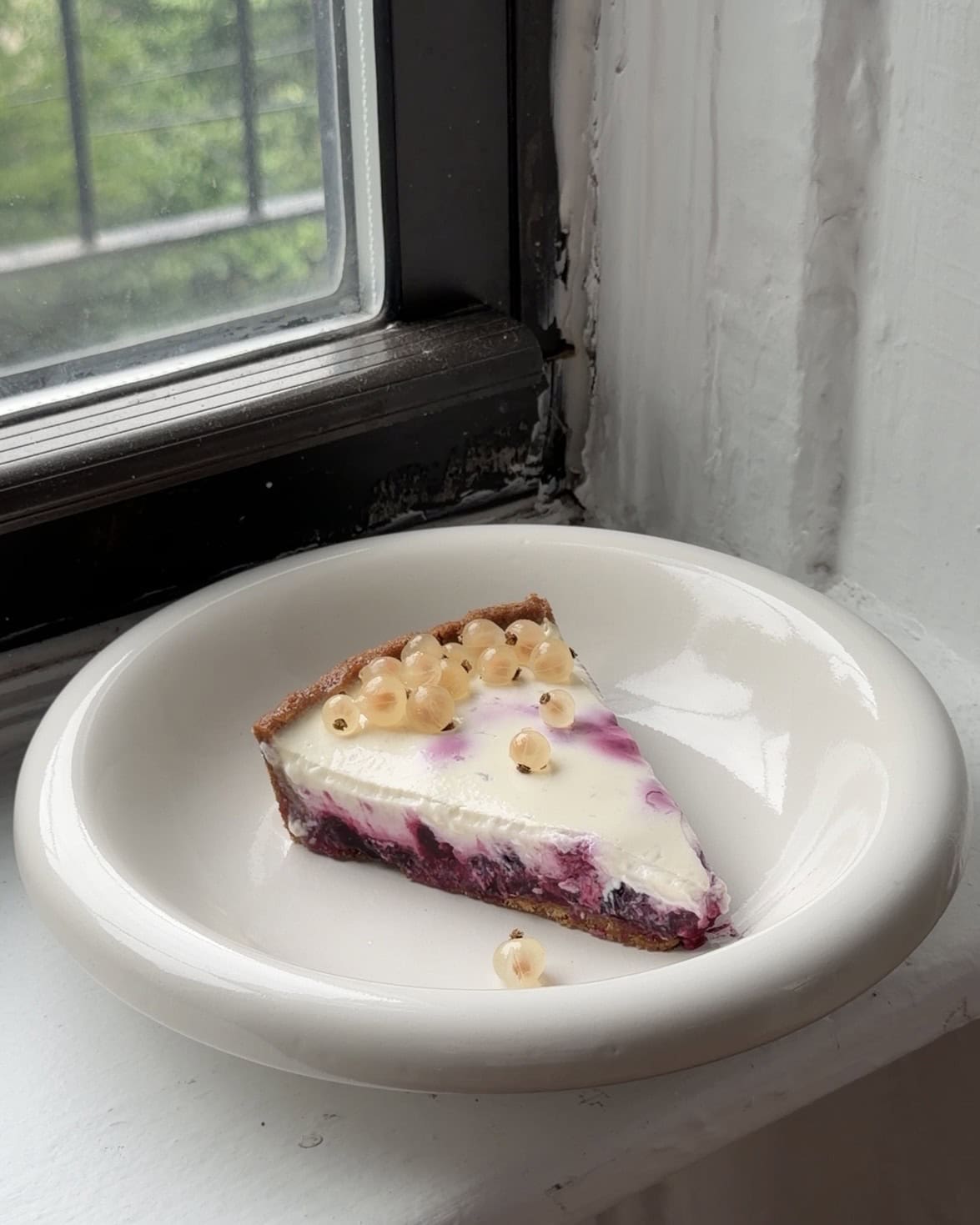Side view of a slice of Currant Panna Cotta Tart on a white plate.