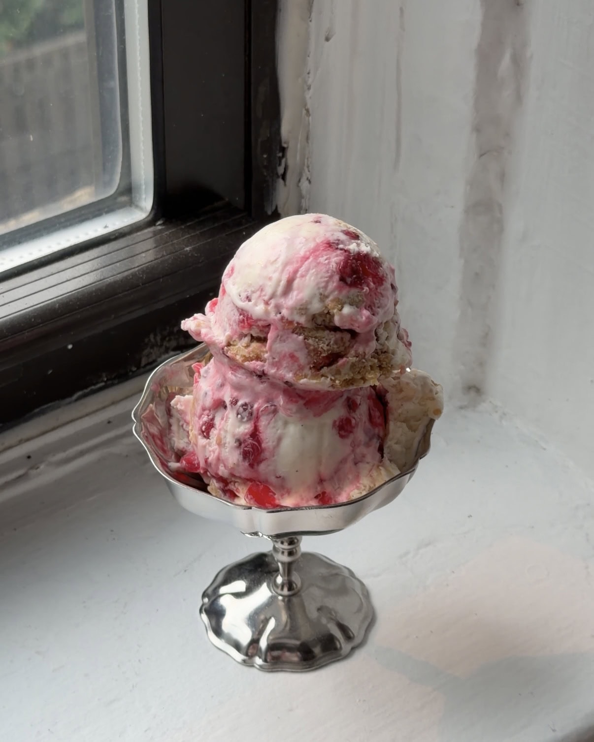 Side view of two scoops of Red Currant Crumble ice cream in a silver coupe glass.