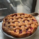 Side view of a sour cherry pie on a baking sheet.