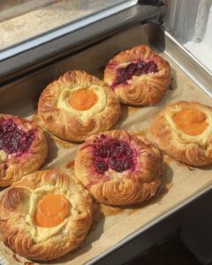 Side view of apricot and raspberry cream cheese danishes on a parchment lined baking sheet.