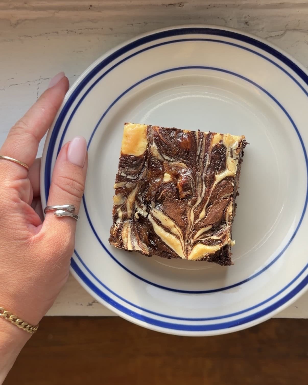 Overhead view of a banana cream cheese brownie on a white and blue plate.