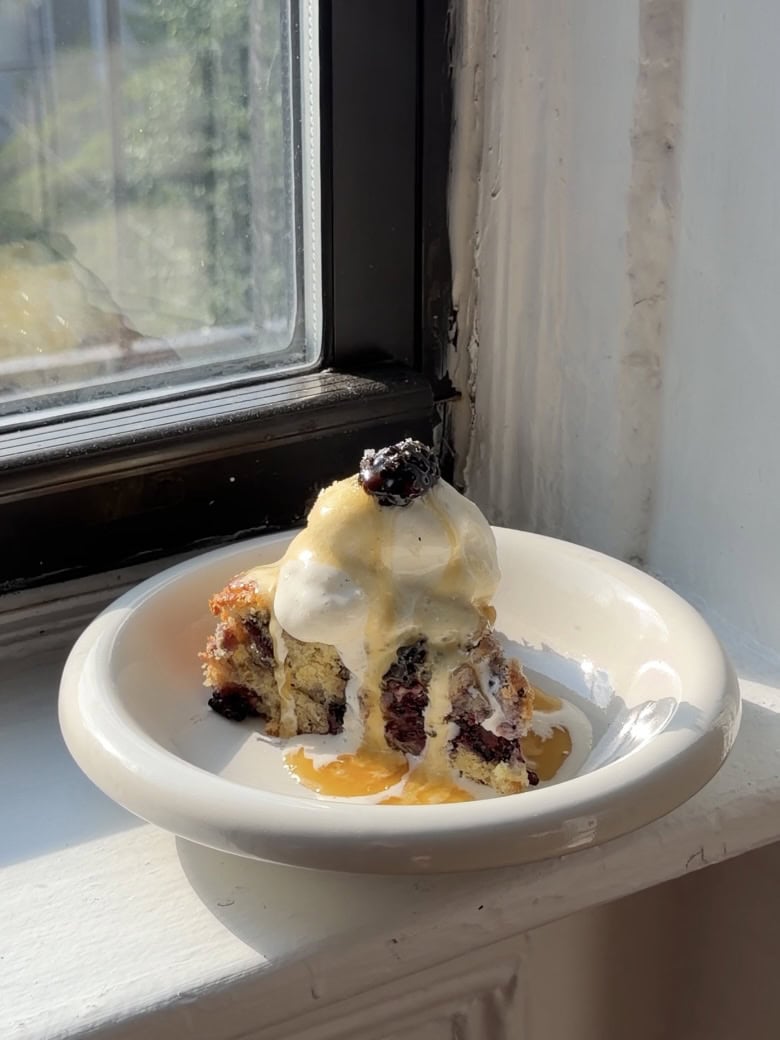 Side view of a slice of Blackberry blueberry biscuit cake on a white shallow bowl.
