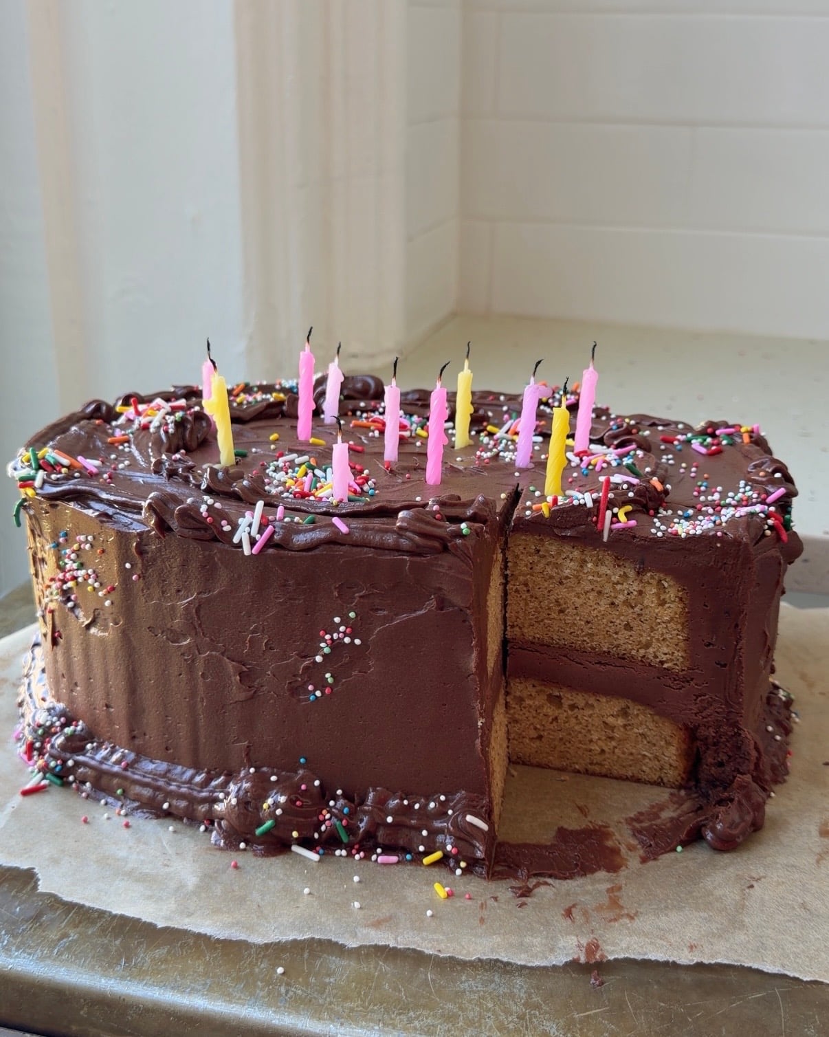 Side view of a whole Brown Butter Cake with Chocolate Cream cheese frosting with a slice taken out showing the layers.