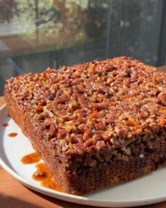 Side view of a Banana Bread Pecan Upside Down Cake on a white plate.