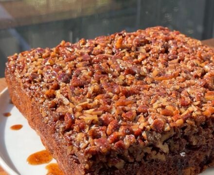 Side view of a Banana Bread Pecan Upside Down Cake on a white plate.