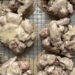 Overhead view of 6 apple fritters with a maple glaze on a wire cooling rack.