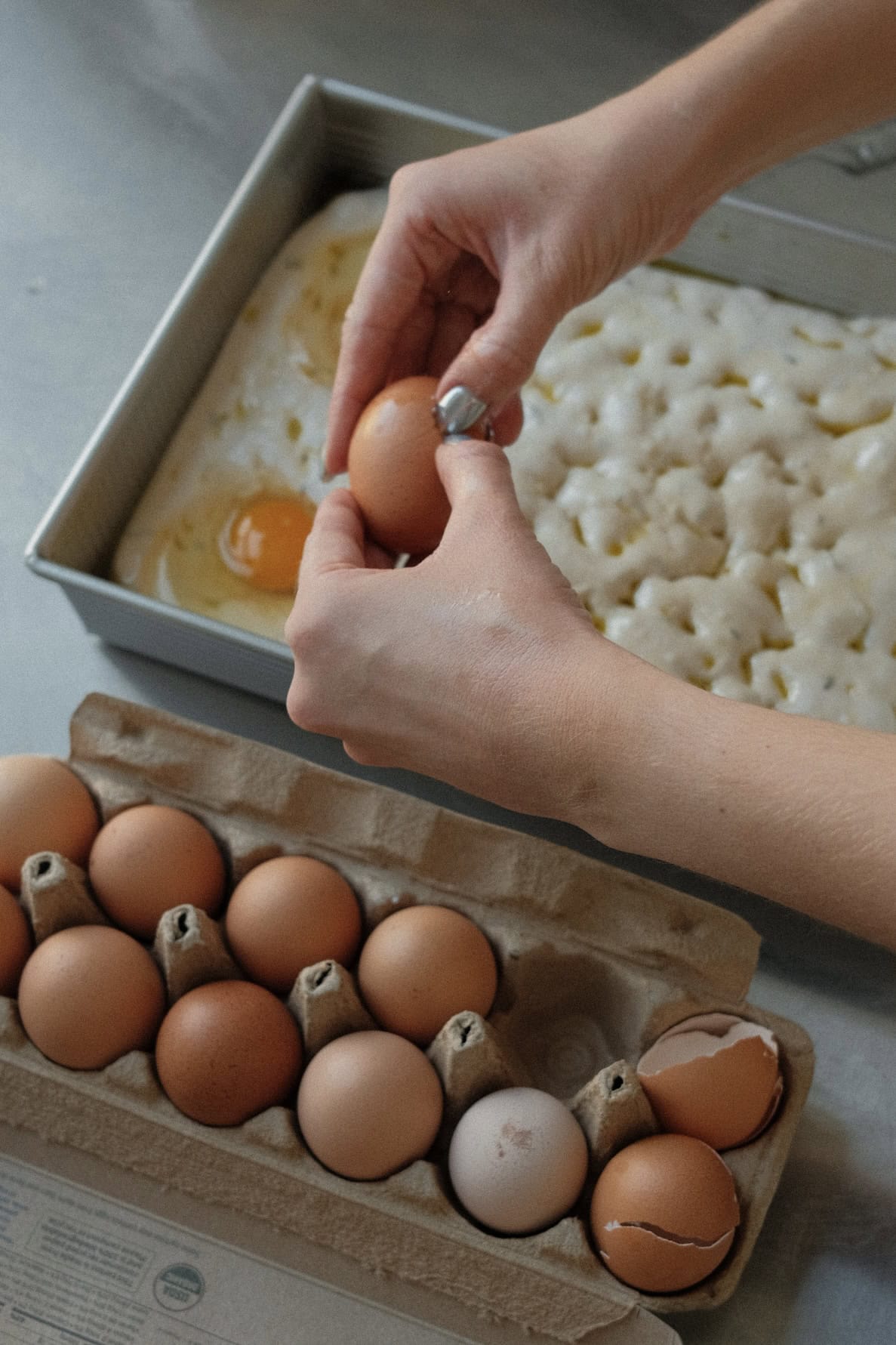 Overhead view of eggs being cracked onto sourdough focaccia.