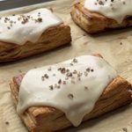 Side view of Cinnamon Apple Toaster Strudels on a parchment lined baking sheet.