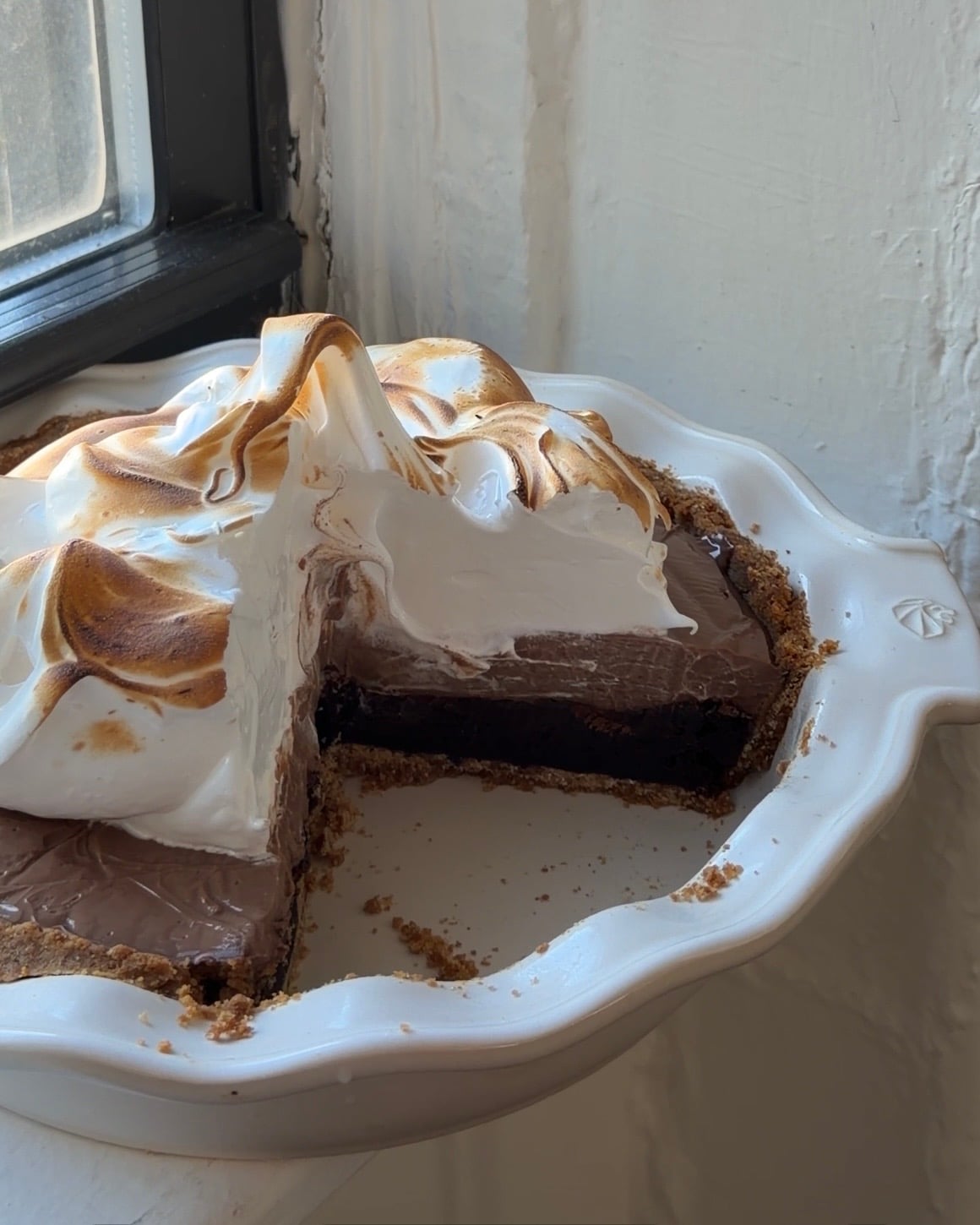 Side view of a S'mores Brownie pie in a white pie dish.