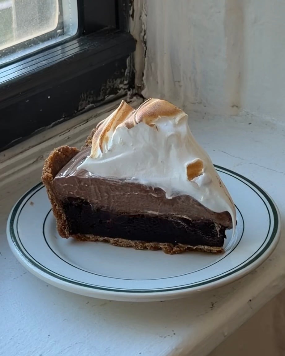 Side view of a slice of S'mores Brownie Pie on a white and green plate. 